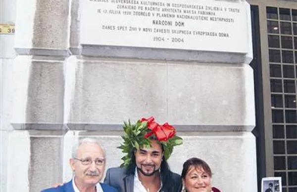 Maturant Paolo s Sardinije s starši pod spominsko ploščo Narodnega doma v Trstu