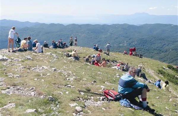 Številni obiskovalci na temenu Snežnika, v ozadju kvarnersko morje in Učka