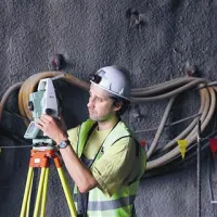 Po vsakem odkopnem koraku geolog preveri strukturo hriba. Geometer (na fotografiji) pa dvakrat na dan izmeri, za koliko se je stisnila  predorska cev. Na koprski strani to zaradi trde kamenine   ni težava. Vijaki v ozadju  so sidra.    