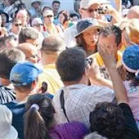 Vidkinja Mirjana si s pomočjo postavnih domačinov v rumenih majicah utira pot med ljudmi