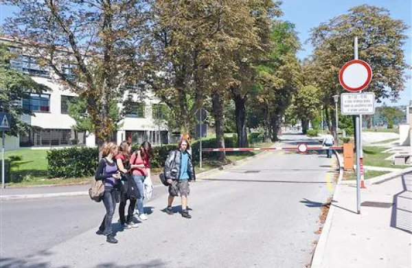 Kosovelova ulica v Sežani je zdaj med 7. in 15. uro zaprta za promet. Občina namerava zaporo ukiniti, šolo ograditi, šolarji pa naj bi v telovadnico in na igrišča hodili po mostu. 