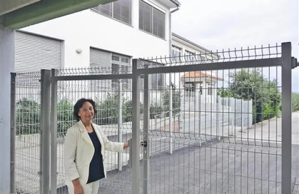 Ravnateljica Maja Cetin ob novi ograji, v ozadju prizidek šole iz leta 2004