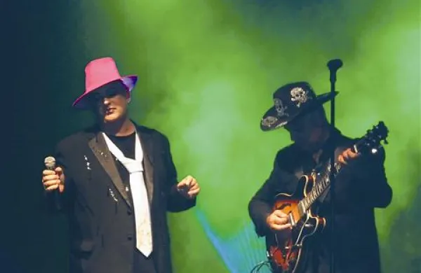 Boy George: na glavi klobuk, pa črna moška svetlikajoča se obleka s hlačami   do sredine meč in  na nogah  teniske 