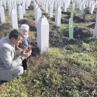 Moški z otrokom na pokopališču Potočari pri Srebrenici, kjer so  pokopane žrtve pokola iz leta 1995