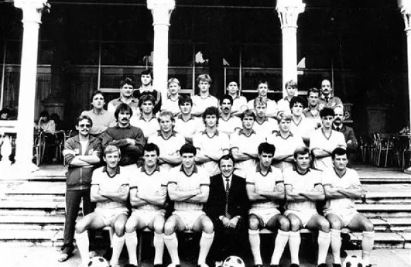 Fotografiranje za klubski koledar pred znamenito kavarno Loggia. Predsednik  Karlo Emeršič (v sredini) s člansko ekipo, ki je v sezoni 1985/86 igrala v 2. jugoslovanski ligi. Starejši bralci boste med pozornim ogledom našli nekaj znanih obrazov