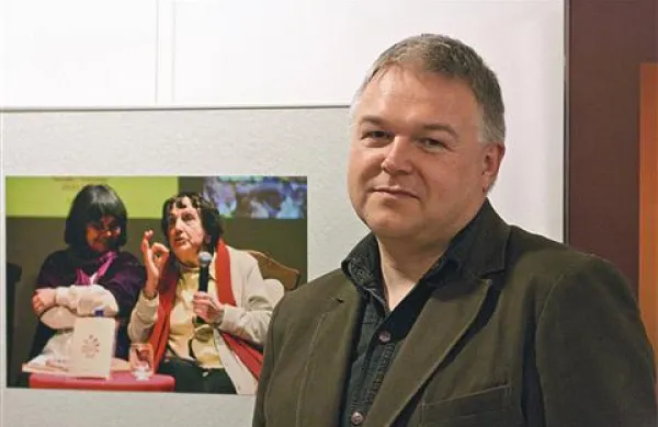 Fotograf Bogdan Macarol pred eno izmed razstavljenih fotografij, ki prikazuje pogovor pesnice Maje Razboršek in Jolke Milič, prevajalke njenih pesmi v italijanščino 