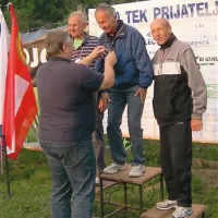 Logaški župan Berto Menard obeša medaljo okrog vratu najhitrejšega med najstarejšimi Lucijana Lipuščka. Levo se je zamislil Albert  Lazar, Fabia Ivančiča (desno) pa zanima, kdo fotografira.