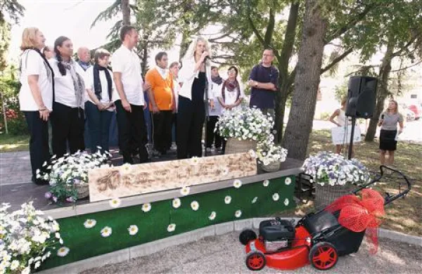 V ospredju podarjena kosilnica, za mikrofonom Tjaša Rodman, direktorica Centra za socialno delo, pod okrilje katerega sodi Barčica  