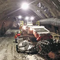 Rezalni stroj. Glava na roki se pomika gor in dol, desno in levo. Zvezdasti kolesi stresata   izkopani material na tekoči trak v zadnjem delu stroja, kjer ga sprejmejo   tovornjaki. Skozi sive cevi ob  stroju odsesavajo zrak, nasičen s prahom.