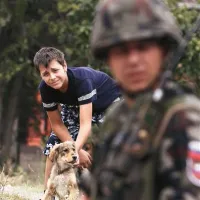 Deček s psom opazuje slovenskega pripadnika enot KFOR na meji med Srbijo in Kosovom
