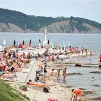 Plaža je delno kamnita, betonirana in peščena.
