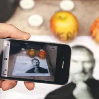 Mimoidoči z iPhonom fotografira spominsko obeležje pred trgovino v Parizu.