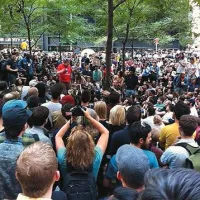 Slavoj Žižek (v rdeči majici) med protestniki v newyorškem parku Zuccatti; park je v zasebni lasti, zato policija tam demonstrantov ne more preganjati. V treh tednih protestov je bilo aretiranih že več kot 1000 ljudi.