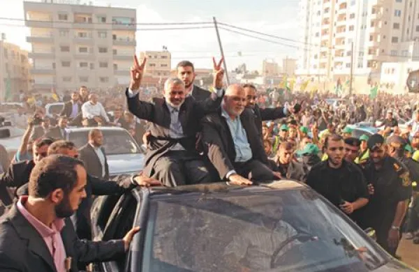Vodja Hamasa Ismail Haniyeh (levo) pozdravlja ljudi, ki so v Gazi pričakali konvoj z izpuščenimi ujetniki. 