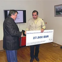 Predsednik Rotary kluba Ljubljana Emona Marjan Koršič predaja denarno pomoč  rotarijcev predsedniku KS Soča Trenta Božidarju Kavčiču 