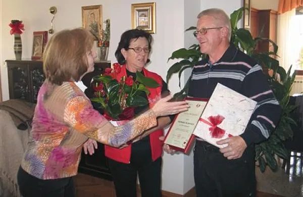 Jožica Vidmar, sekretarka bistriške OZ RKS (levo), izroča Jadranu Boštjančiču, ob ženi Nadi, priložnostno darilo