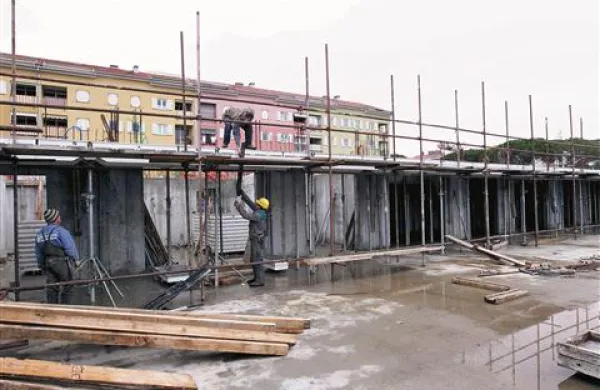 Na novogradnji Oktobrska delavci te dni odstranjujejo gradbene odre. V ozadju je že zgrajen kompleks, ki se ga je oprijel vzdevek Alcatraz. 