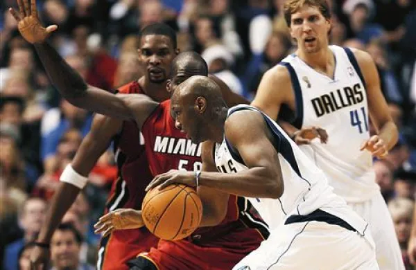 Oslabljeni zmagovalci lige Miami Heat  so v uvodu izgubili z Dallasom. Krilo  Lamar Odom se prebija mimo  Joela Anthonya (v ospredju)   in  Chrisa Bosha (oba Miami), opazuje pa jih nemški športnik leta Dirk Nowitzki (Dallas)