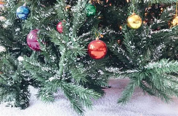 Neznanec se je znesel nad okrašenim božičnim drevescem. Fotografija je simbolična