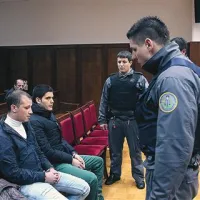 Russa (levo) in Zambettija spremljajo pazniki v neprebojnih jopičih, noge pa imata ves čas vklenjene