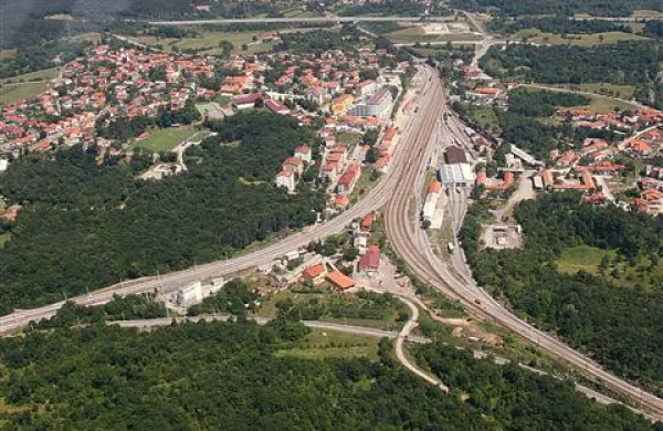 Pogled iz zraka na divaški trikotnik (spodnji del slike) in Divačo (levo od proge). Med prenovo železniške postaje bodo zgradili podhod do južnega dela mesta (na desni strani), do trikotnika pa ni predviden.