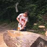 Kiparka Ana Žerjal v lipov les dolbe drevak, plovilo, ki bo prav kmalu plulo po Soči.