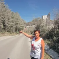 Predstavnica pogajalske skupine v Lažah Martina Žetko kaže na zeleno območje ob kamnolomu, v neposredni bližini vasi, ki je tako onesnaženo s prahom iz kamnoloma, da so tam morali opustiti kmetovanje