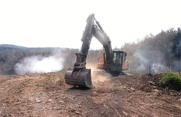 Z materialom zasipavajo strm nasip, sredi katerega pod tlemi gori, skozi špranje pa se dviguje dim ostrega in zadušljivega vonja