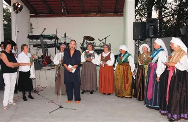 Članice  krožka Noša, pesmi in plesi naših non v nošah skupaj z  Marto Košuta (ob mikrofonu)