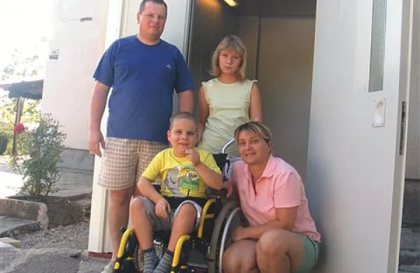 Sedemletni Žiga Krebelj z družino ob nepogrešljivem dvigalu, za katerega so na Bistriškem in drugod v okviru humanitarne akcije zbrali denar  