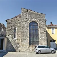 Pogled na začelje cerkve, ki je stisnjena med med koprsko gimnazijo (desno) in ekonomsko šolo   