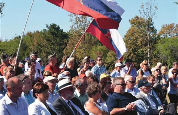 Slovenske zastave z rdečo peterokrako in gostje proslave