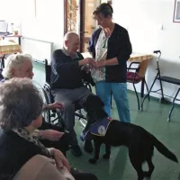 Labradorka Kuba čaka na nagrado -  briket, shranjen v žepu terapevtke Lilijane Slavec (desno)
