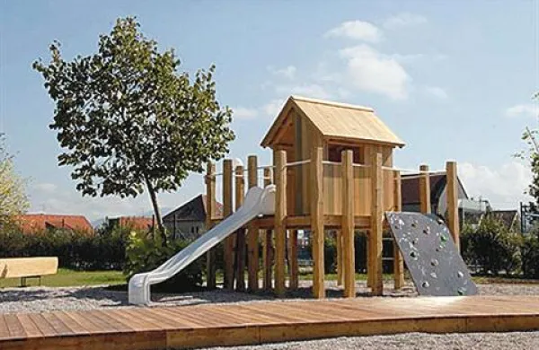 Otroško igrišče na Vrhniki; prispodoba mostiščarske hiše z ljubljanskega barja za plezanje in skrivanje. Spredaj “pomol” za posedanje skrbnikov v “peščenem jezeru”
