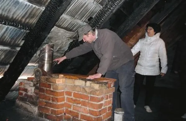  Stanovalec Zvonko, ki je prvi gasil,  z Romano Kranjc kaže na dimnik, kje je zagorelo