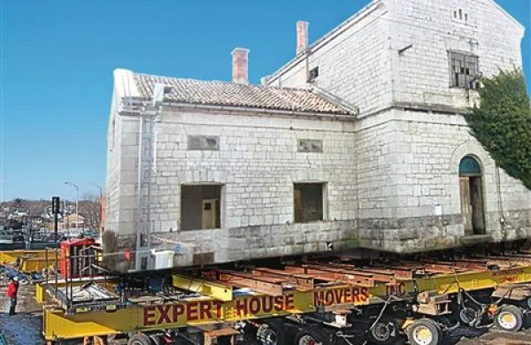 Fotomontaža prikazuje, kako bi lahko  premestili kamniti vodni stolp s hidravličnimi dvigali. Z istimi   so prestavili cerkev v Massachusettsu v  ZDA (z nje smo “sneli” dvigala in jih “podstavili” pod divaški stolp). Tudi v Sloveniji so na ta način že uspešno  prestavili nekaj objektov. 