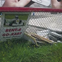 Tabla z urnikom, ki je vabila na karting stezo, je odvržena ob ograji 