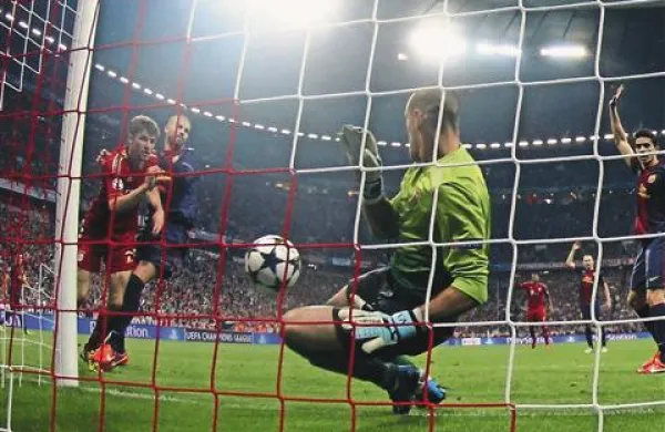 Thomas Müller (levo)  se je izognil  Gerardu Piqueju (za Müllerjem) in zatresel mrežo.  Šokirani vratar Barcelone Victor Valdes (v ospredju) je moral kar štirikrat po žogo v mrežo.