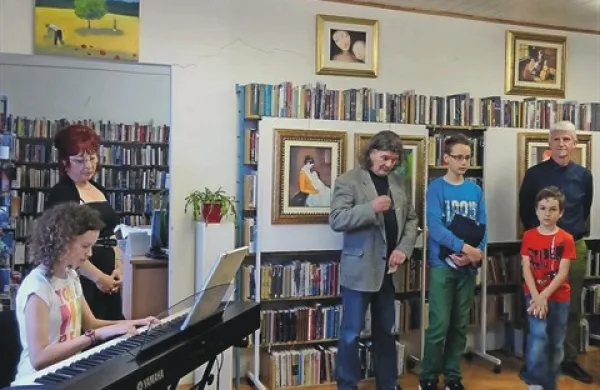 V  komenski knjižnici je na ogled postavila svojo prvo slikarsko razstavo  Nadja Lozej (na fotografiji stoji ob pianistki) iz Vojščice na Krasu, kjer živi in ustvarja