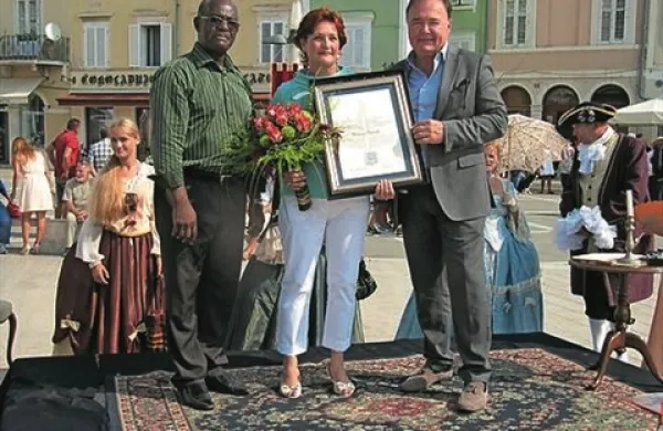 Piranski župan Peter Bossman (levo) in direktor turističnega združenja Portorož Jadran Furlanič sta Mariji Terčelj podelila  priznanje občine Piran grb odličnosti v turizmu 