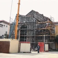 Pogled na začelje nekdanje cerkve s športnega igrišča na stičišču koprske gimnazije (rumena stavba) in srednje ekonomske šole (bela stavba)