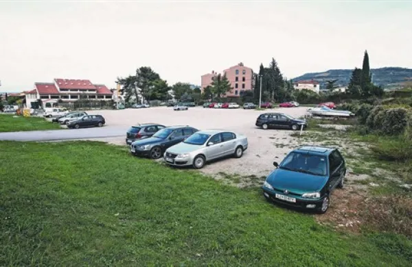 Makadamsko parkirišče je v prazničnih dneh precej prazno. Povsem drugače pa je, preden se začne pouk, vrtec ali kakšna prireditev v hali.   
