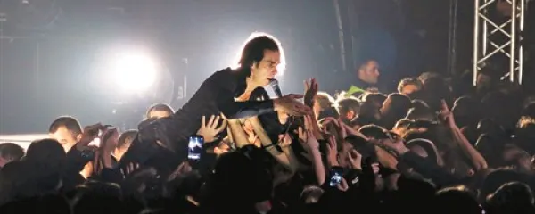 Svetopisemski prizor v rocku: pridigar Nick Cave na rokah svojih častilcev  med ponedeljkovim koncertom v prepolni manjši dvorani Hale Tivoli 