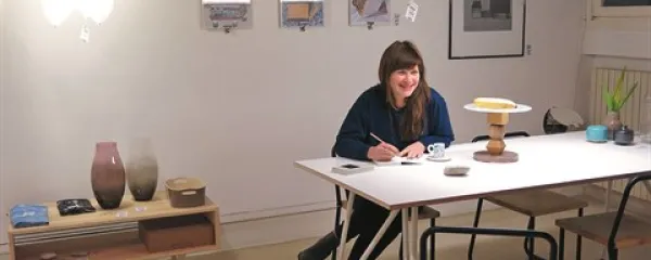 Nina Mršnik v Pop-up domu Benetke v družbi slovenskih oblikovalskih stvaritev: desno  čajna mizica Ogler koprskega oblikovalskega dua Toktok (Andrej Koruza in Matej Rodela),  na steni kolaži Lucie Massari, desno slika Zorana Pungerčarja Soba,  na mizi 