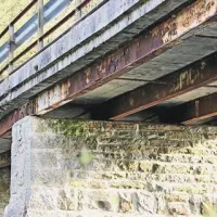 Pogled pod suhorski most razkriva zarjavelo železno konstrukcijo, popuščanje in krušenje betona, kot da se bo most vsak čas vdal, zrušil in omahnil v reko Reko