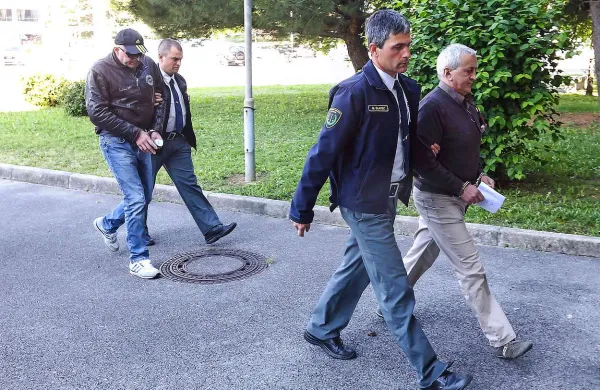 Mario Bonalda (zadaj) in Ruggero Marcassoli (spredja, oba v spremstvu paznikov) se na koprskem sodišču zagovarjata zaradi ropa banke v Sežani