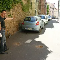 Boris Stepančič kaže na precej zaparkirano Ulico agrarne reforme, pred njim pa sta luknji v asfaltu, kjer sta do sobote stala sporna stebrička