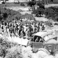 Skupina primorskih Slovencev iz 215. posebne kazenske čete (poznejših pripadnikov partizanske čete Primorje) ob prevozu na delo za popravljanje ceste Lixouri - Argostoli na otoku Kefalonija avgusta 1943