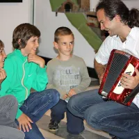  Marko Hatlak s svojo prvo harmoniko, Miklavžem, Stašem in Anžetom na učni uri