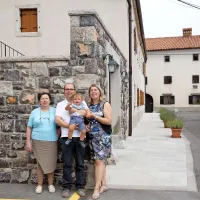 Marta, Andrej in Blaž Muha ter Helena Godina pred nekdanjim senikom, v katerem so uredili sobe za goste, zadaj je gostilna Muha